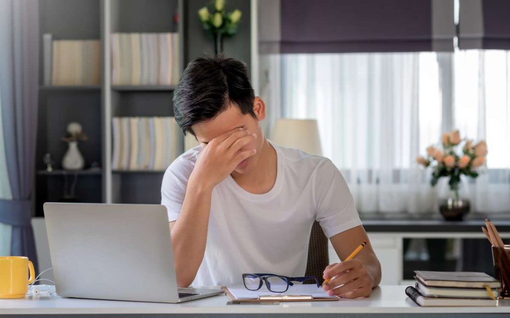 Un empleado con fuerte migraña, pensando si necesita un justificante laboral para ausentarse al trabajo.