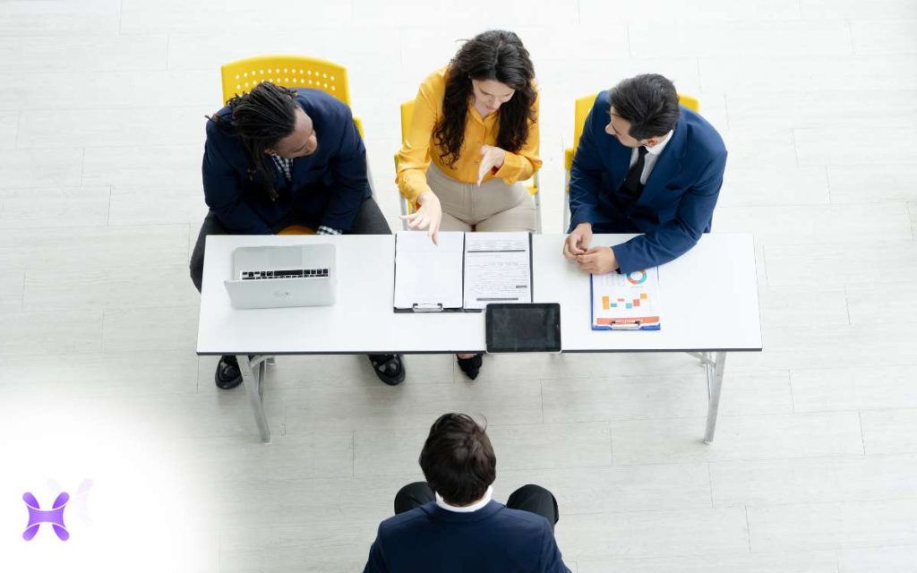 En la imagen se ve al área de recursos humanos sentados en una mesa aplicando el assessment center con un nuevo candidato. 